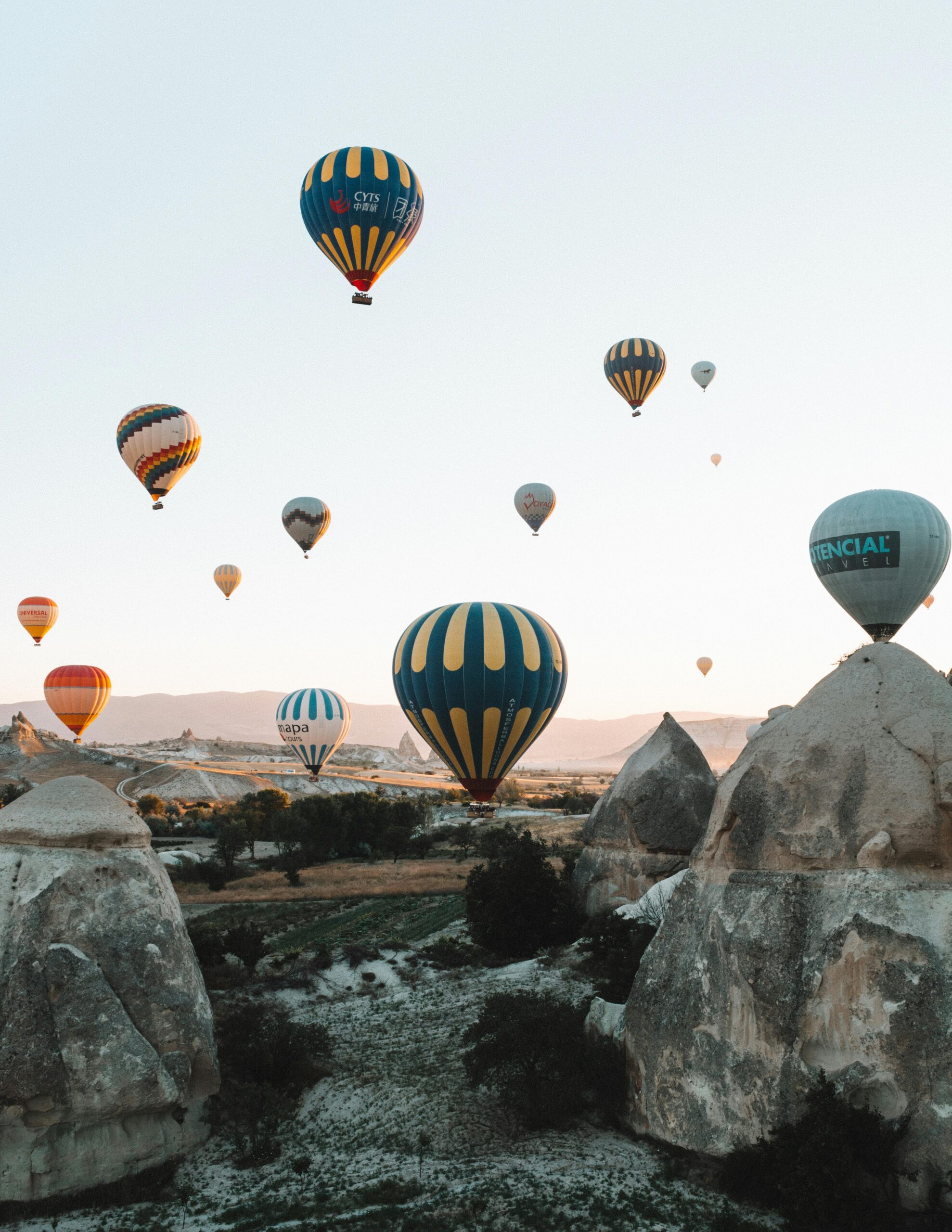 Vibrant hot air balloons soaring over the unique rock formations of Cappadocia at sunrise.